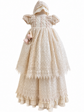 Load image into Gallery viewer, An ivory-colored lace baby dress with a matching bonnet, featuring short puff sleeves, a smocked bodice, and a tiered ruffled skirt, shown against a plain white background.
