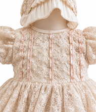 Load image into Gallery viewer, A close-up of a baby girl's dress and bonnet set in ivory-colored lace, featuring pale pink satin vertical trim with pearl-like beads and puffed sleeves.
