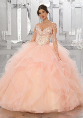 A young lady wearing a quince dress in the color champagne/blush.