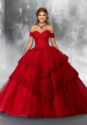 A young lady wearing a tiered ballgown with off-shoulder sleeves in the color red.