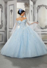 Load image into Gallery viewer, A young lady wearing a ballgown with cape in the color light blue.
