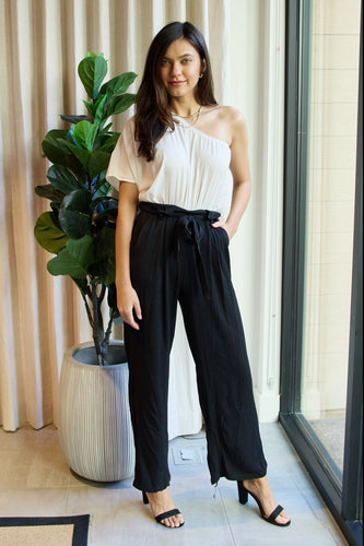 The front view of a young lady wearing an asymmetrical jumpsuit in back/white.
